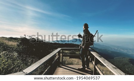   Asian hipster men backpacker enjoying take a photo on beautiful landscape background scenery view jungle mountains green forest at Doi Inthanon National Park, Chiang Mai, Thailand.