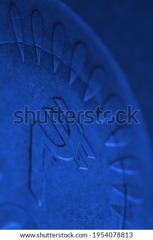 Translation: rupee. Fragment of Indian 10 rupee coin with a national currency symbol close-up. The very dark blue vertical background or backdrop. Money, banking and finance of India. Macro
