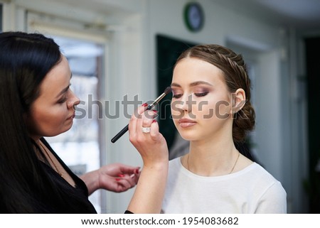 Bride getting ready for wedding. Professional make-up artist painting female clients' eyes in brown color. Work process in beauty studio. Love yourself retreat Close-up picture on make-up model.