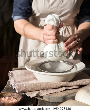 Preparation of almond milk - woman straining the milk through a cheesecloth Royalty-Free Stock Photo #1954093186