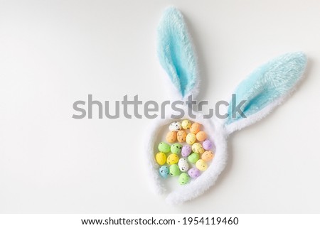 Bunny ears and colored little eggs on white background on Easter day. Top view. Symbol Happy Easter holiday concept. Flat lay. Copy space.