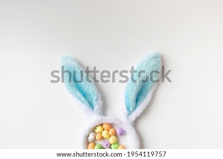 Bunny ears and colored little eggs on white background on Easter day. Top view. Symbol Happy Easter holiday concept. Flat lay.