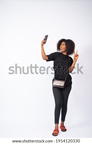 attractive young nigerian lady taking a selfie with her phone
