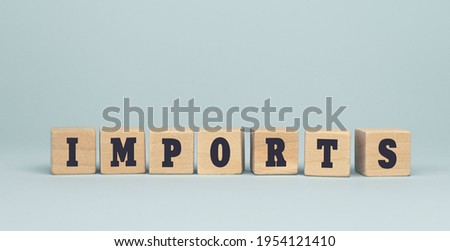 The word IMPORTS made from wooden cubes on blue background. Conceptual photo