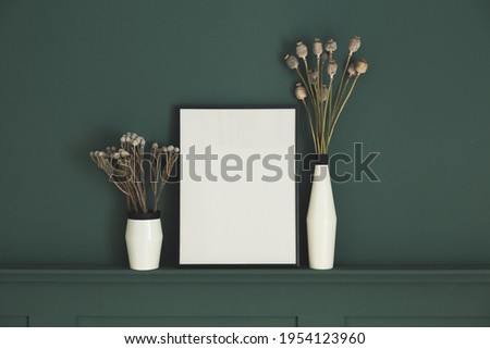 Poster frame mock-up and vase with poppies on dark green paneled wall 