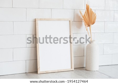 Vertical poster mockup and dried flowers in vase on table. Brick tiles wall on background. Scandinavian home decor, nordic style. Photo frame mockup.