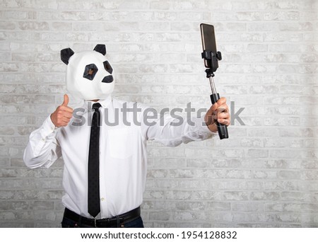 Man wearing a panda mask took a picture with his mobile phone