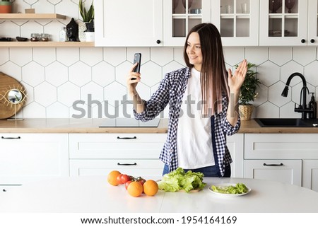 Girl food blogger conducts a live broadcast in the kitchen, shows how to cook healthy food. High quality photo
