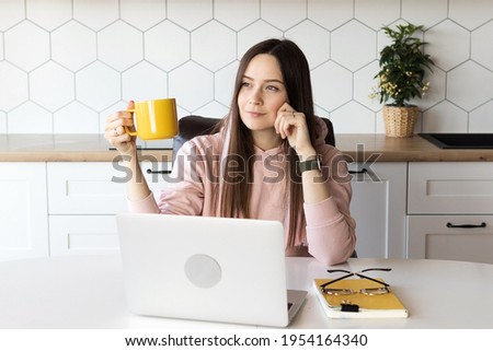 Woman takes a break from work and drinks tea, online work at a laptop. High quality photo