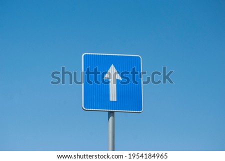 Blue rectangle one way road traffic sign closeup on blue sky background