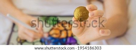 BANNER, LONG FORMAT NFT Young woman, a digital artist, creates digital art on a tablet at home and shows a coin with the inscription NTF - non fungible token. Remote work, digital nomad, digital