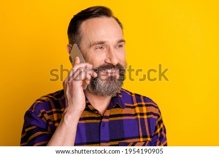 Photo of happy relaxed mature man hold smartphone talk smile enjoy isolated on yellow color background
