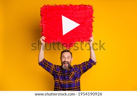 Photo of excited happy mature man raise big play video icon above head isolated on yellow color background