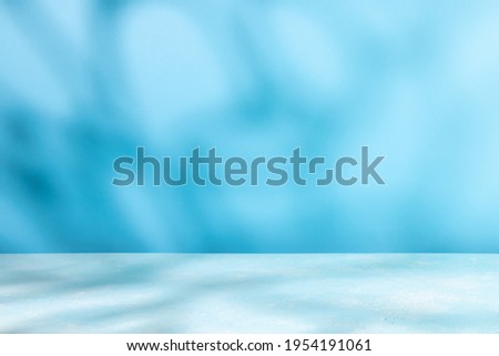 Abstract shadow on table top and blue wall background. Blurred backdrop with copy space.