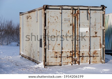 Rusty gray cargo container stands on snow, industrial shipping equipment Royalty-Free Stock Photo #1954206199
