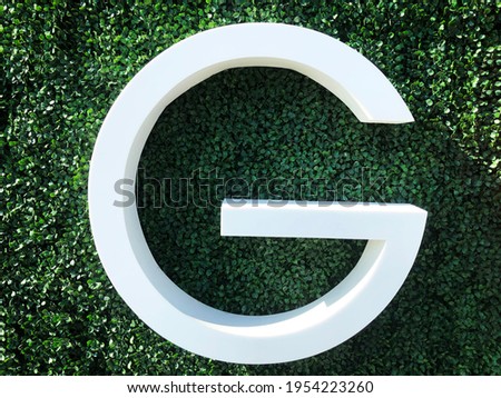 big white letter G photographed on green grass outdoors