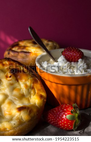 Open pie with cream cheese, bowl of cottage, fresh strawberries on a table. Pink background. Breakfast close up photo. 