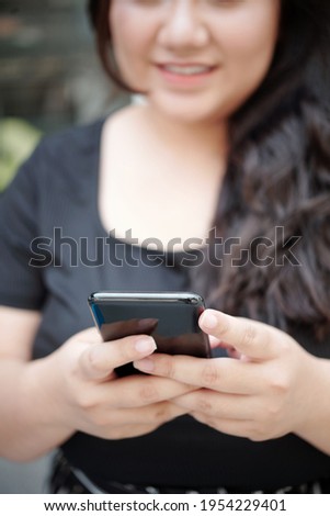 Close-up image of young woman using application on smartphone or texting friends