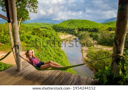 Beautiful young caucasian tourist relaxing on a hammock in National Park Phong Nha Ke Bang, Vietnam. Rural scenery photo taken in south east Asia - one of the most pretty vietnamese places.