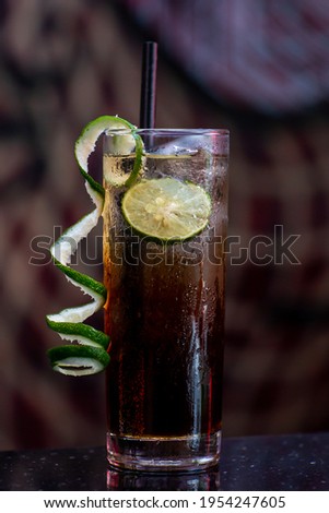 Exotic Long island ice tea cocktail in front of dark background garnished with lime peel