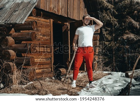 Young Man coming out of chalet with wooden stick. 