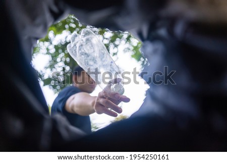 man throws garbage into a garbage can on the street. With a worm view from the inside of the trash bin. Selective focus. Environment and business concept.