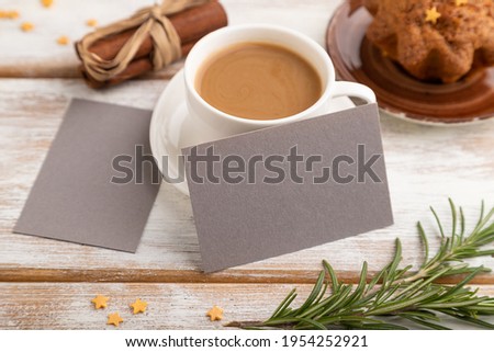 Gray paper business card mockup with cup of coffee and cake on white wooden background. Blank, side view, still life.