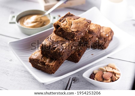 Caramel and Chocolate peanut butter tart pie with slices and nuts an peanut butter on white wood background 