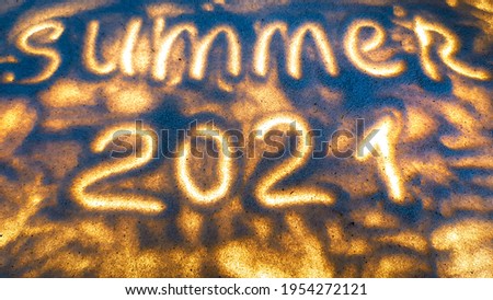 the inscription on the sand summer 2021 glows. Royalty-Free Stock Photo #1954272121