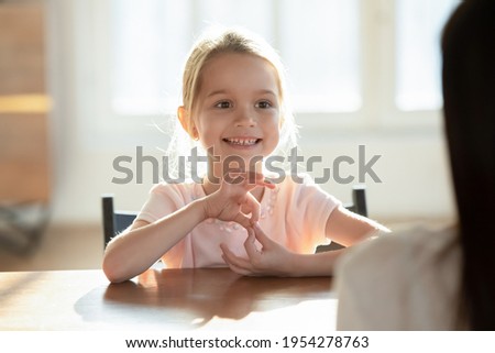 Cute little Caucasian girl child speak talk engaged in educational activity with mom or nanny at home. Small kid study distant learn pronouncing sounds with teacher or tutor. Education concept.