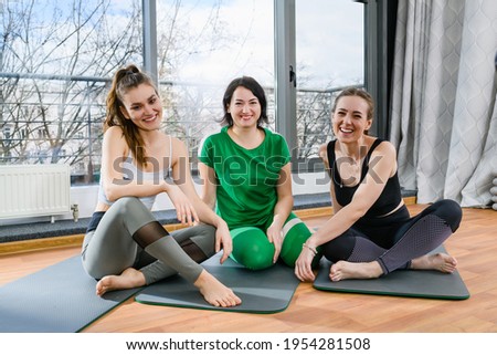 Happy fitness girls sit and smile indoors