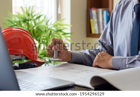 Architect man or male engineer hand stamping rubber stamper on  blueprint paperwork at office. Authorized allowance permission approval concept. Royalty-Free Stock Photo #1954296529