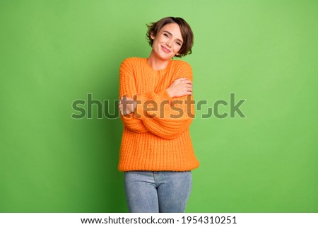 Photo of joyful happy young cute woman hug herself comfort good mood isolated on green color background