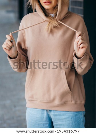 Fasion blonde woman in brown oversize hoodie, glasses and blue jeans, mockup for logo or branding design