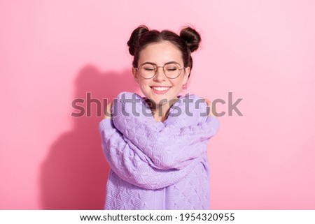 Photo portrait of cute girl in glasses dreaming embracing herself isolated on pastel pink color background with copyspace