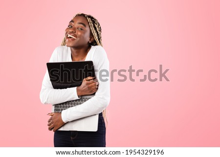 Happy Black Woman With Afro Braids Hugging Laptop Computer With Blank Screen Posing Standing Over Pink Studio Background And Looking Aside At Free Copy Space. Online Technology, Advertisement, Mock Up
