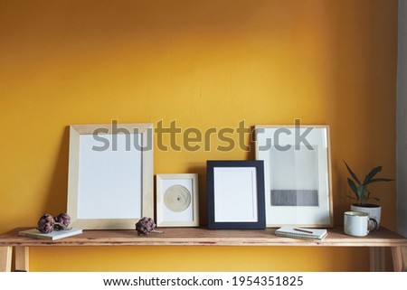 Modern graphics on a yellow background. Composition with a flowerpot, dried artichokes, a notebook and a cup. Against the background of a yellow wall