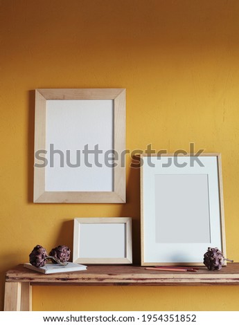 Wooden frames mockup. Composition with a dried artichokes, and book . Against the background of a yellow wall