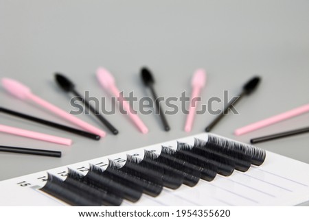 A tablet with false eyelashes and brushes on a black background. Cosmetic accessories for eyelash extensions Royalty-Free Stock Photo #1954355620