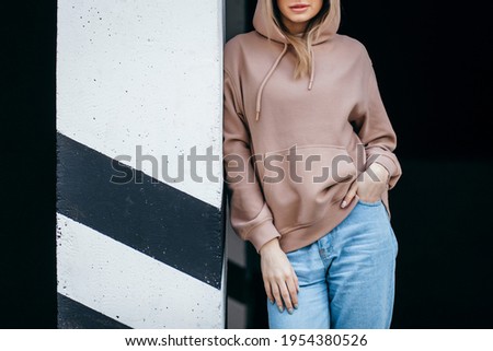 Fasion blonde woman in brown oversize hoodie, glasses and blue jeans, mockup for logo or branding design Royalty-Free Stock Photo #1954380526