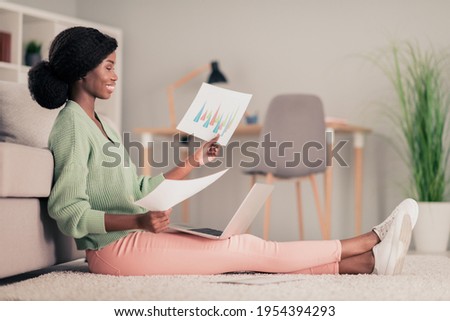 Full body profile side photo of young african woman sit floor home analyze documents project report laptop