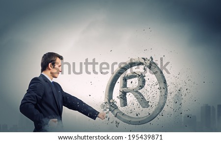 Angry businessman crashing stone trademark with karate punch