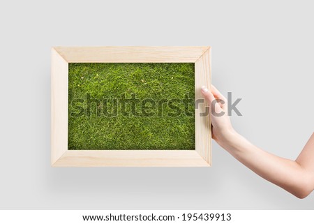 Close up of hand holding frame with green grass