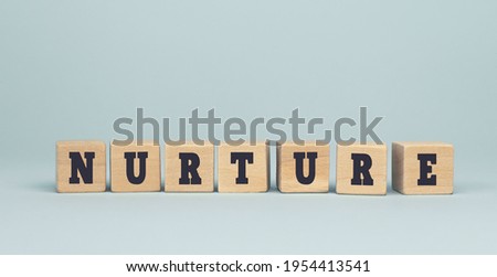 The word NURTURE made from wooden cubes on blue background. Conceptual photo