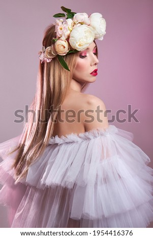 Beauty portrait art woman long hair light transparent puffy dress, bright beauty red makeup. Wreath of rose flowers on girl head. Red lipstick and eye shadow. Woman on pink background