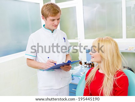 Closeup portrait happy, smiling female patient, woman sitting in chair, dental office clinic, answering questions male health care professional, dentist asking her. Doctor taking patient notes history