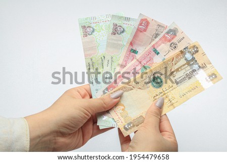 Female Hands holding UAE money 500,200,100, on white background 