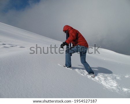 Woman walking bravery to the top of a snow mountain, facing danger and difficulties to reach the peak. Osorno region in southern Chile. Royalty-Free Stock Photo #1954527187
