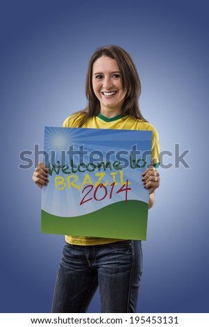 Female Brazilian Fan holding a welcome to Brazil sign, on a blue background.
