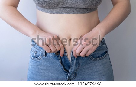 The girl cannot button a button on her pants Royalty-Free Stock Photo #1954576666